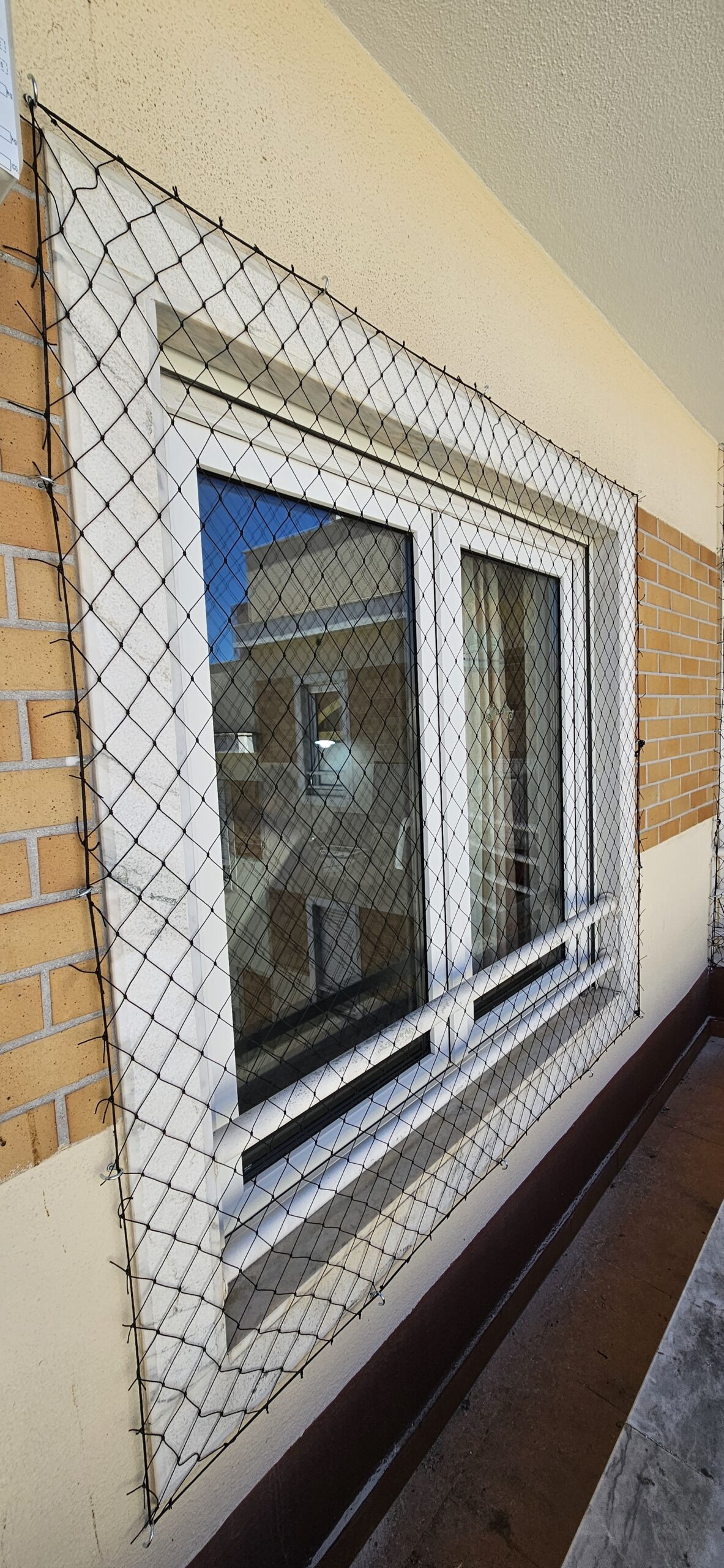 Proteção infantil com rede de segurança em janela de apartamento